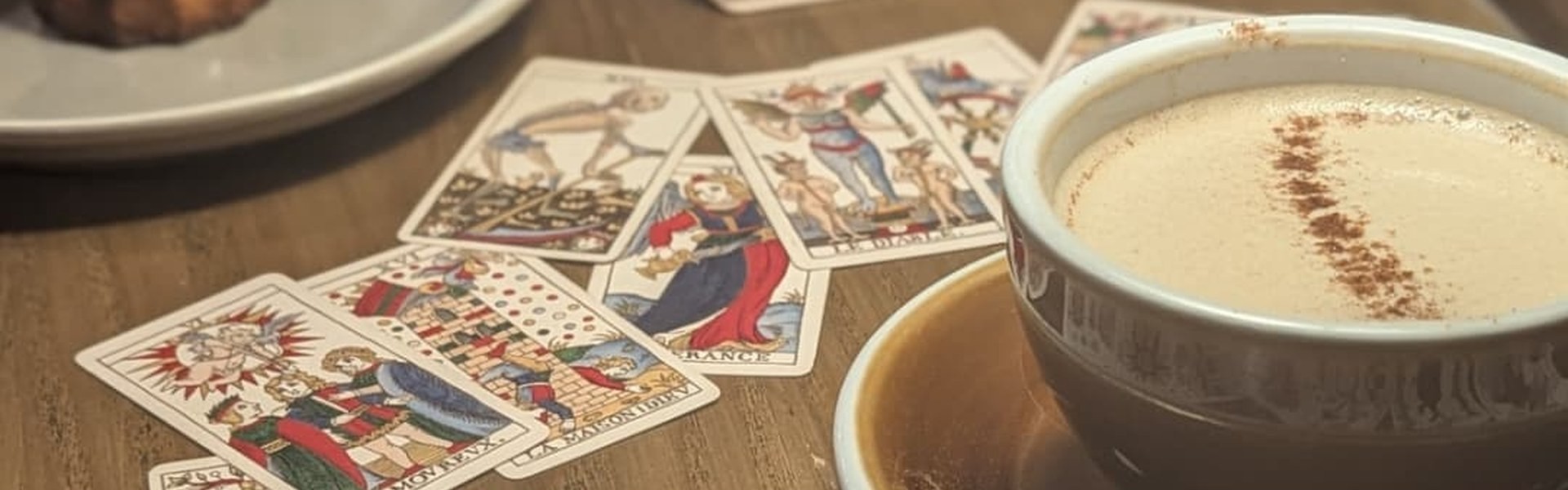 咖啡杯上緣與桌上展開的法式馬賽塔羅牌
